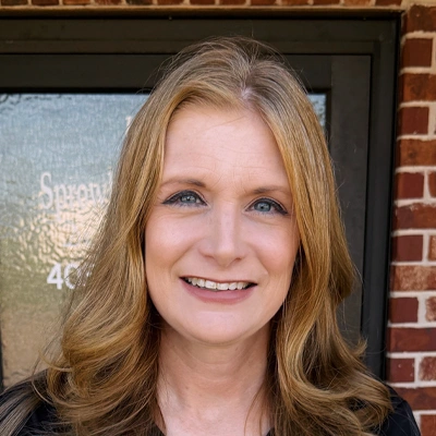Professional headshot of a person with shoulder-length light brown hair